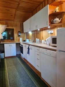 a kitchen with white appliances and wooden walls at Między Sosnami in Jedwabno