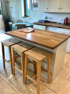 eine Küche mit einem Holztisch und 2 Hockern in der Unterkunft Mulberry Barn Annx - Self Contained Near Winchester in Micheldever