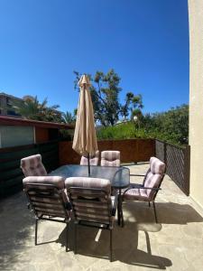 eine Terrasse mit einem Tisch, Stühlen und einem Sonnenschirm in der Unterkunft Corner townhouse in Regina Gardens, Pafos in Paphos City