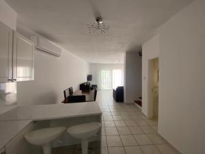 eine weiße Küche mit einer Theke und ein Wohnzimmer in der Unterkunft Corner townhouse in Regina Gardens, Pafos in Paphos City