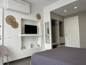 1 dormitorio con 1 cama y TV en la pared en CALA AZZURRA MACARI Bed and Breakfast and Holidays House, en Macari