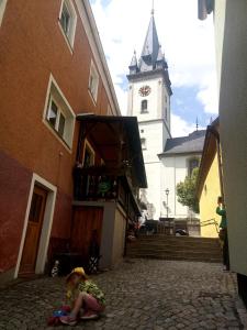 una niña sentada en el suelo cerca de un edificio con una torre de reloj en POLKA, en Schwarzenbach an der Saale
