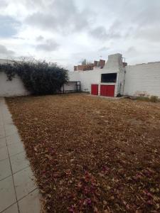 um grande quintal com um edifício branco com uma porta vermelha em Casa Familiar para hasta 6 personas , Lujan de Cuyo , Mendoza em Ciudad Lujan de Cuyo