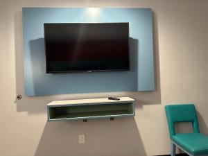 a flat screen tv hanging on a wall with two chairs at La Casa Motel, Los Angeles - Burbank Airport in Sun Valley