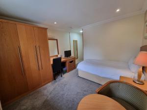 a bedroom with a bed and a desk with a computer at Kegworth Hotel East Midlands Airport in Castle Donington