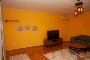 ein Wohnzimmer mit gelber Wand und TV in der Unterkunft Vila Omar in Sarajevo