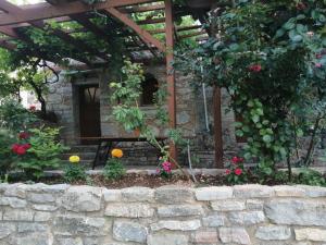 un jardín con flores y una pared de piedra en ΑΝΑΒΑΤΟΣ ΕΞΟΧΙΚΗ ΚΑΤΟΙΚΙΑ ΙΙ, en Chios