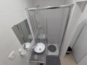 uma casa de banho branca com um chuveiro e um lavatório. em Room Dream Beato em Lisboa