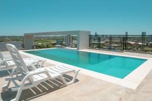 a swimming pool on the roof of a building with two chairs at Elegante monoambiente en Asunción, Luque. in Luque
