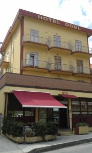 a hotel with a red awning in front of it at Hotel Nuova Doel in Sottomarina