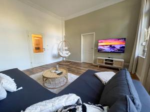 sala de estar con sofá azul y TV de pantalla plana en Bamboo City en Magdeburgo