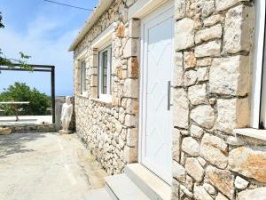 een stenen gebouw met een witte deur en een raam bij Angelos Stone Cottage in Ágios Nikólaos