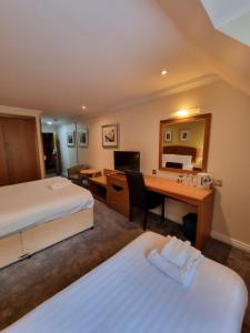 a hotel room with two beds and a desk at Kegworth Hotel & Conference Centre in Castle Donington