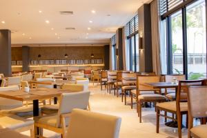 a restaurant with tables and chairs and windows at JL Hotel by Bourbon in Foz do Iguaçu