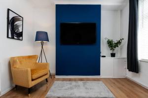un soggiorno con parete blu, sedia e TV di Manchester Urban Chic Hideaway a Manchester