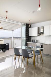 une cuisine et une salle à manger avec une table et des chaises en verre dans l'établissement Hilltop Apartments - Stylish Comfort Living close to the sea, Bugibba, à San Pawl il-Baħar