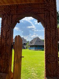 an open door to a field with a house in the background at La patru daci in Ocna Şugatag