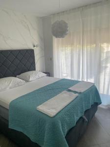 een slaapkamer met een bed met een groene deken en een raam bij Tijara Apartment in Rijeka