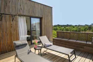 2 chaises et une table sur une terrasse en bois dans l'établissement Villa en bordure de vignoble 6 personnes à la semaine, à Marseillan