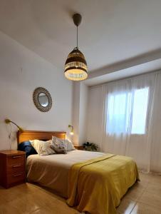 a bedroom with a bed with a yellow blanket and a window at La viajera Espadan in Algimia de Almonacid