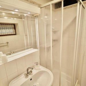 Un baño blanco con ducha y lavabo. en Duenenrose, en Tinnum