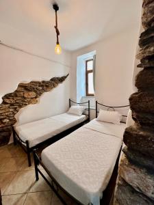 2 camas en una habitación con una pared de piedra en Pallada Boutique Tinos, en Tinos