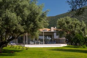 a house with a green lawn and trees in front of it at Averto Villas with private pool in Nydri