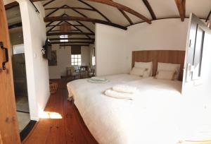 Schlafzimmer mit einem großen weißen Bett und Holzböden in der Unterkunft Bed & Breakfast de Hoefstal in Noord-Sleen