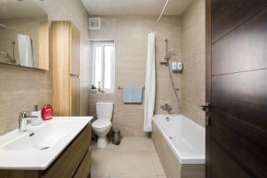 La salle de bains est pourvue d'un lavabo, de toilettes et d'une baignoire. dans l'établissement Hilltop Apartments - Stylish Comfort Living close to the sea, Bugibba, à San Pawl il-Baħar