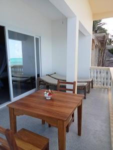 Camera con tavolo e sedie in legno sul balcone. di Kome beach Apartment one a Jambiani