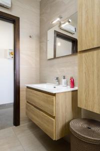La salle de bains est pourvue d'un lavabo et d'un miroir. dans l'établissement Hilltop Apartments - Stylish Comfort Living close to the sea, Bugibba, à San Pawl il-Baħar