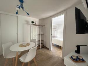 Via Giardini Rooms في فيلاسيميوس: طاولة بيضاء وكراسي في غرفة بها سرير