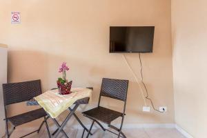 een tafel en stoelen met een tv aan de muur bij Chalés Ilhabela Esmeralda in Ilhabela