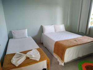 2 camas en una habitación pequeña con faldas en Chalés Ilhabela Esmeralda, en Ilhabela