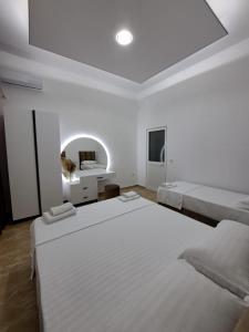 Dieses weiße Zimmer verfügt über 2 Betten und einen TV. in der Unterkunft VILA PUSHIMI REGIS in Velipojë