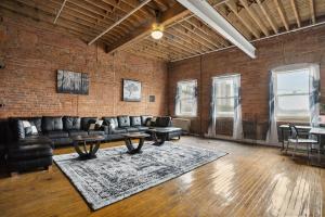 a living room with leather furniture and a brick wall at Downtown Detroit Loft - Fully equipped & Absolutely Gorgeous theme in Detroit