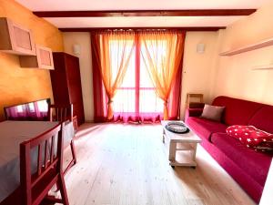 a living room with a red couch and a table at La Casa Bianca - ski, hike & bike in Passo del Tonale +40 photos