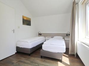 two beds in a room with a window at Holiday Home in Noordwijk with Sunny Garden in Noordwijk aan Zee