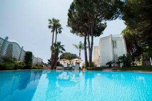 a large swimming pool with palm trees and a building at Vento Verde Apartments in Sperlonga