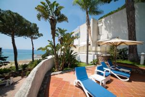 twee blauwe en witte stoelen en een parasol en het strand bij Vento Verde Apartments in Sperlonga