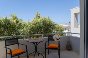 patio z 2 krzesłami i stołem na balkonie w obiekcie Divine Apartments w mieście Kounoupidiana