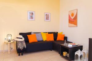 uma sala de estar com um sofá preto com almofadas coloridas em Divine Apartments em Kounoupidhianá