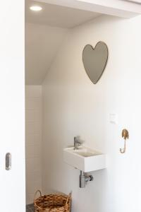 een badkamer met een wastafel en een hart aan de muur bij Zeezicht Villa Duin vlak bij strand en zee in Bergen aan Zee
