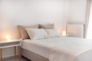 a white bedroom with a white bed and two lamps at Villa Rodanthi Sivota in Syvota