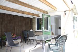 a patio with a glass table and chairs at De Bosrand grenzend aan het bos in Castricum