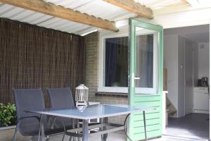 einen Tisch und Stühle auf einer Terrasse mit einem Fenster in der Unterkunft De Bosrand Unieke plek grenzend aan het bos in Castricum