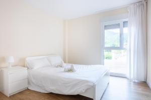 - une chambre blanche avec un lit blanc et une fenêtre dans l'établissement Sukarrieta Home, à Pedernales