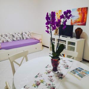 ein Zimmer mit einem Tisch mit einer Vase mit lila Blumen in der Unterkunft LA TERRAZZA DI BASILIO in Olginate