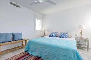 a white bedroom with a blue bed and a window at Puerto Banus Harbour View Apartment in Marbella