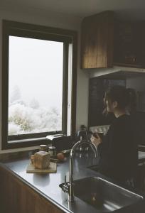 a woman sitting in a kitchen sink next to a window at MenardsNZ Ecosanctuary Accommodation in Twizel